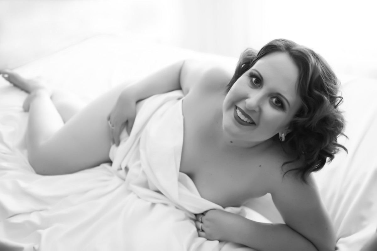 Brisbane Boudoir Photography black and white photo of client posing on a bed wrapped in a sheet